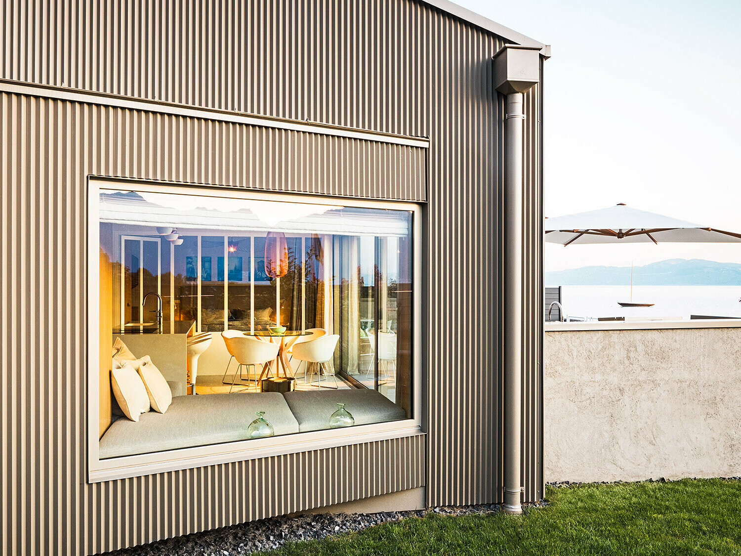 Bygningen med takket aluminiumsfacade set fra siden; en del af det belyste interiør kan ses.