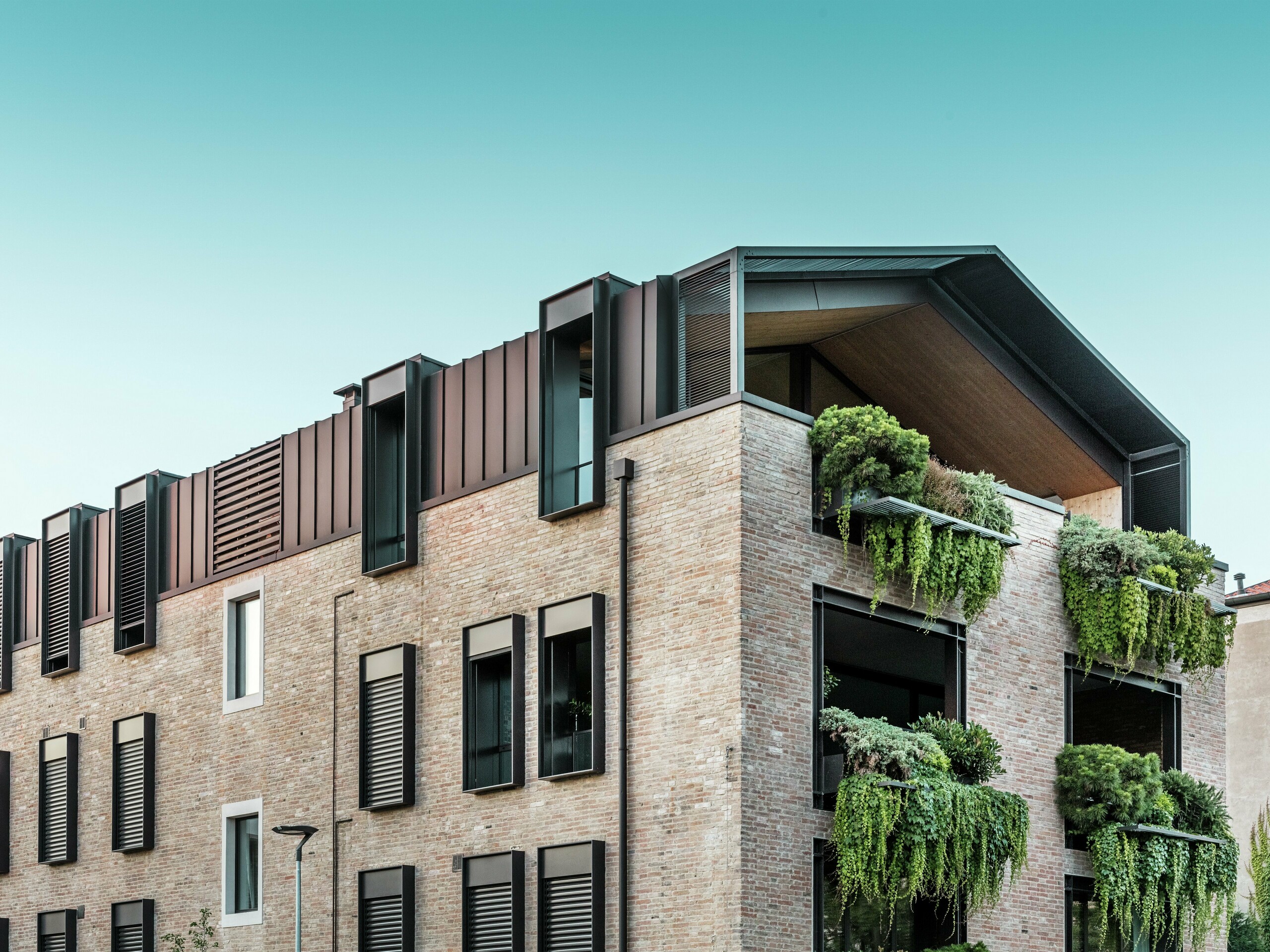 Održiva stambena kuća u Italiji s PREFALZ aluminijskim krovom u boji P.10 smeđa lješnjaka i visećim vrtovima na južnoj fasadi – klimatski aktivna arhitektura s opekom i zelenilom.