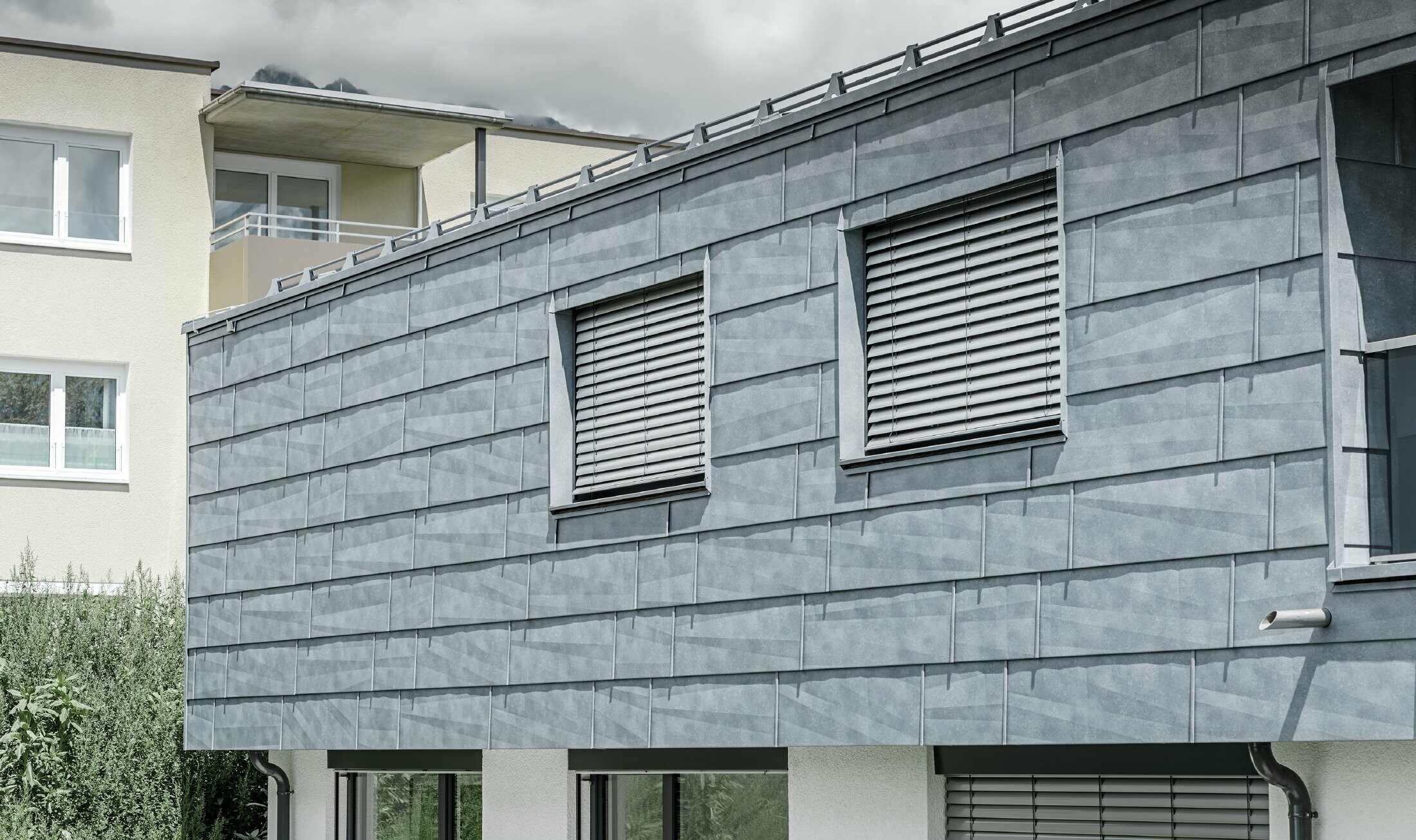 Facadefladeområde med to vinduer. Facaden er beklædt med PREFA facadepanel FX.12 i stengrå.