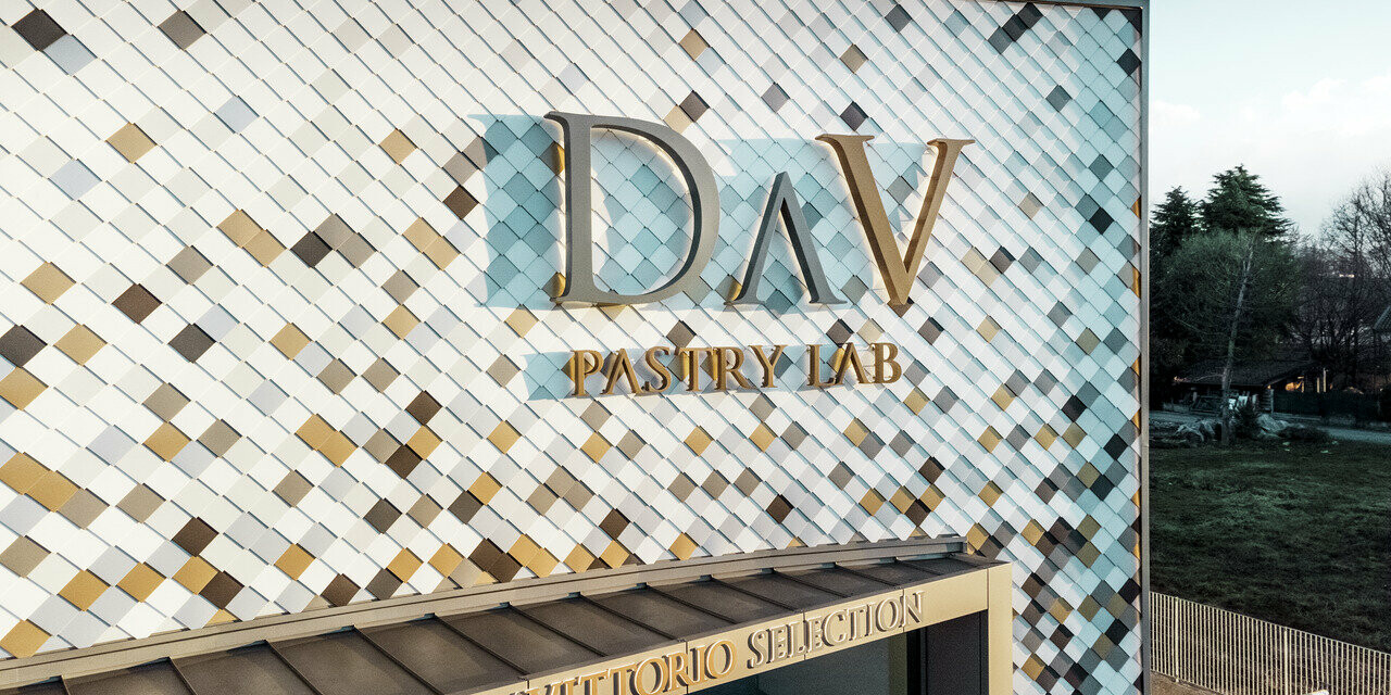 DAV Pastry Lab's firmabygning i Bergamo med spættet vægrombefacade i farverne P.10 brun, bronze, P.10 mørkegrå, mayaguld, naturblank, P.10 Prefa-hvid og P.10 ren hvid 