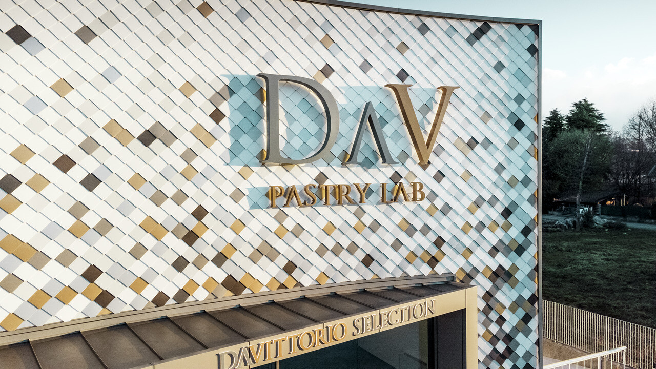 DAV Pastry Lab's firmabygning i Bergamo med spættet vægrombefacade i farverne P.10 brun, bronze, P.10 mørkegrå, mayaguld, naturblank, P.10 Prefa-hvid og P.10 ren hvid 