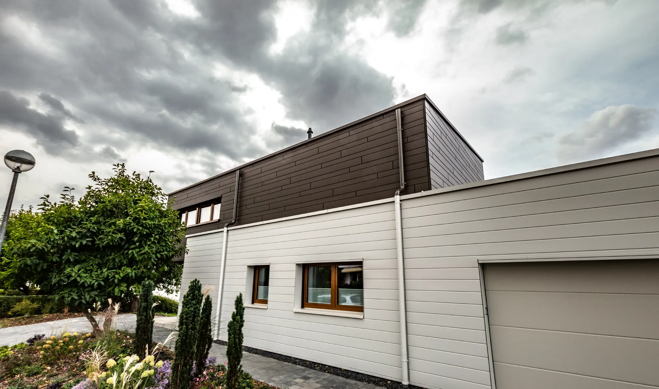 Facadebeklædning på en garage med vandret PREFA Siding i hvid, med tagbrønd.