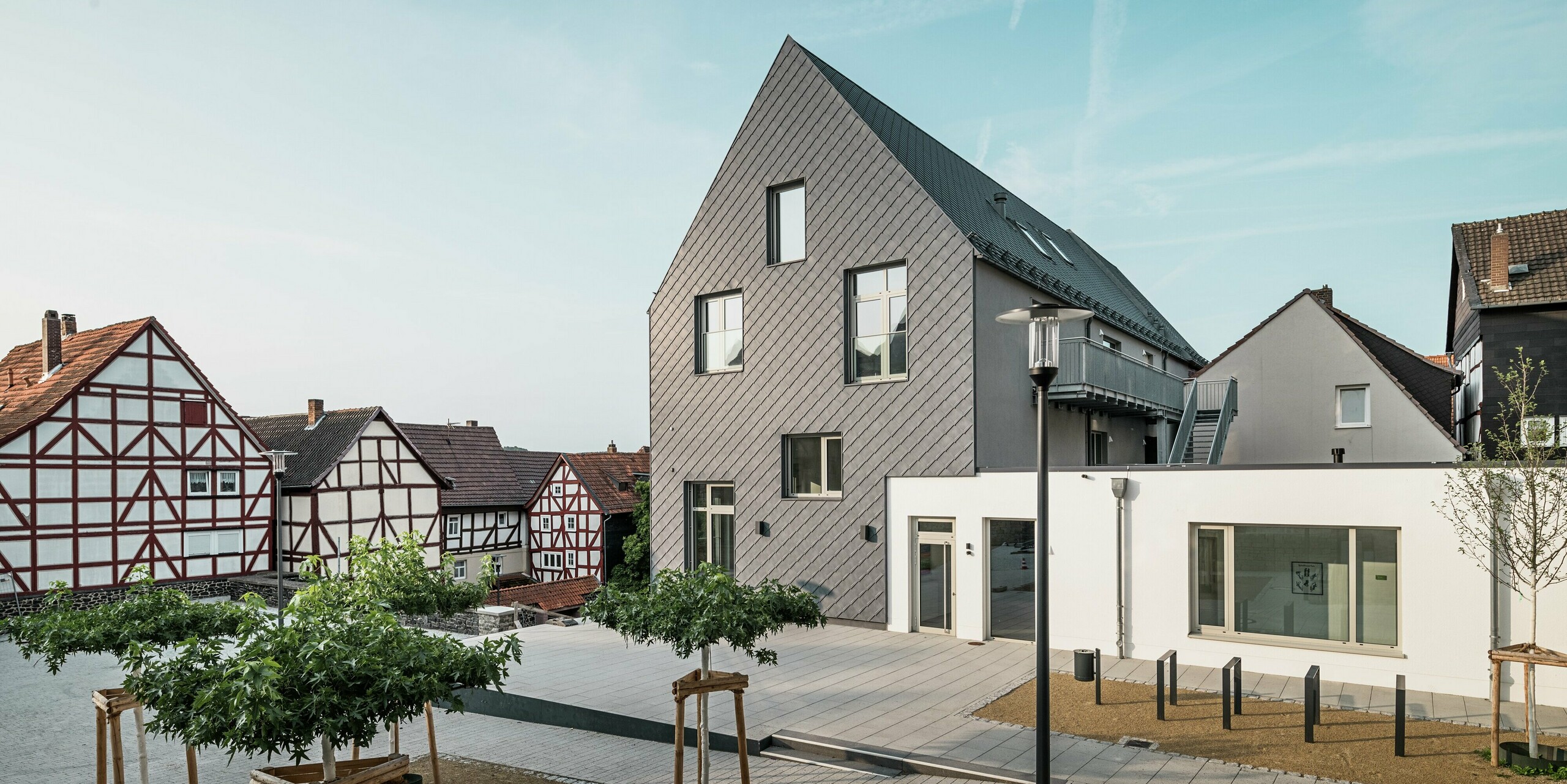 Rückansicht des modernisierten Volkshauses in Homberg, DE, mit PREFA Wandrauten 29 × 29 in P.10 Steingrau. Die elegante Fassade verbindet modernes Design mit den historischen Fachwerkhäusern der Umgebung und bietet Witterungsschutz, Langlebigkeit und zeitlose Ästhetik.
