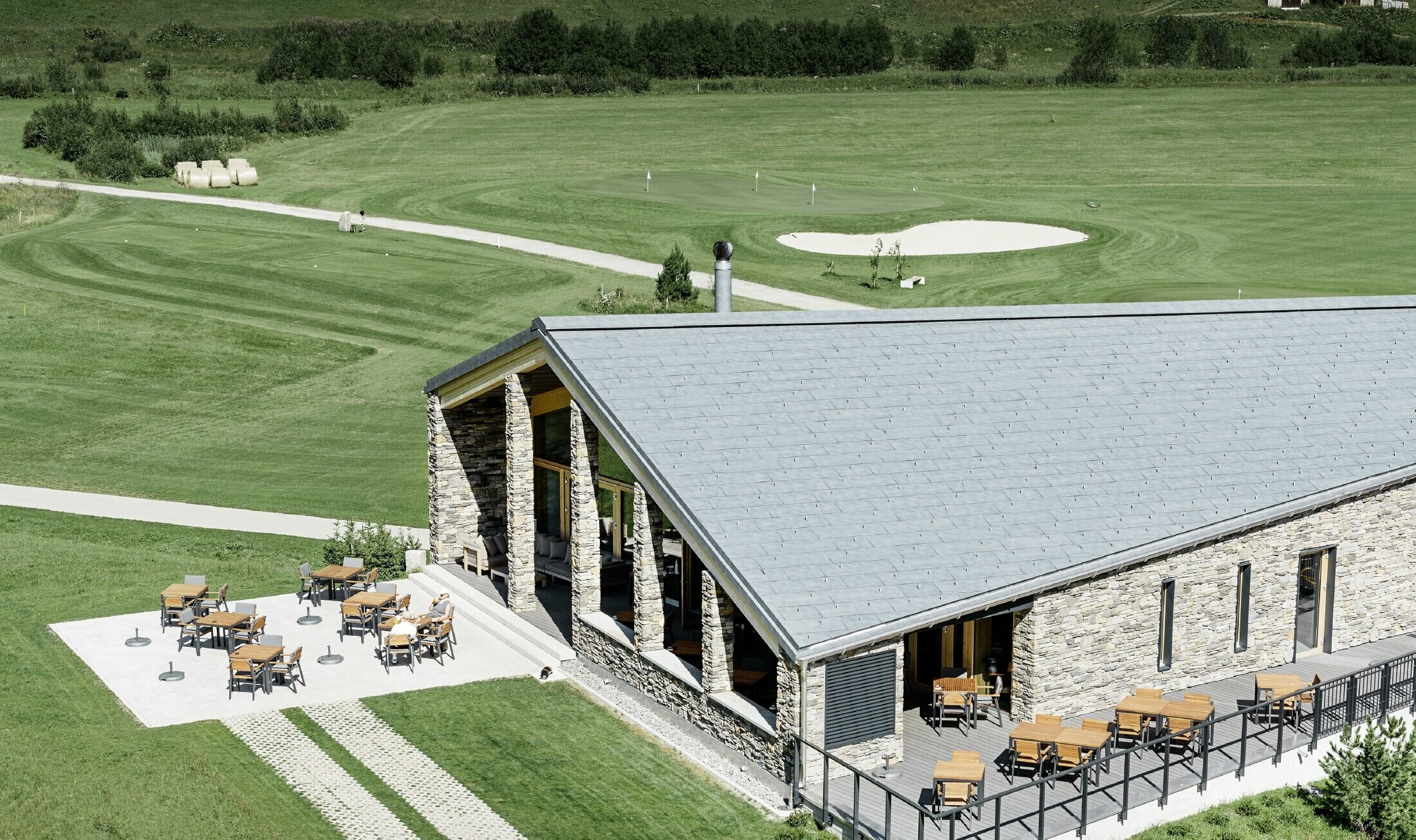 Moderne klubhus på golfbanen i Andermatt med stenfacade og PREFA tagpanel FX.12 i aluminium i stengrå