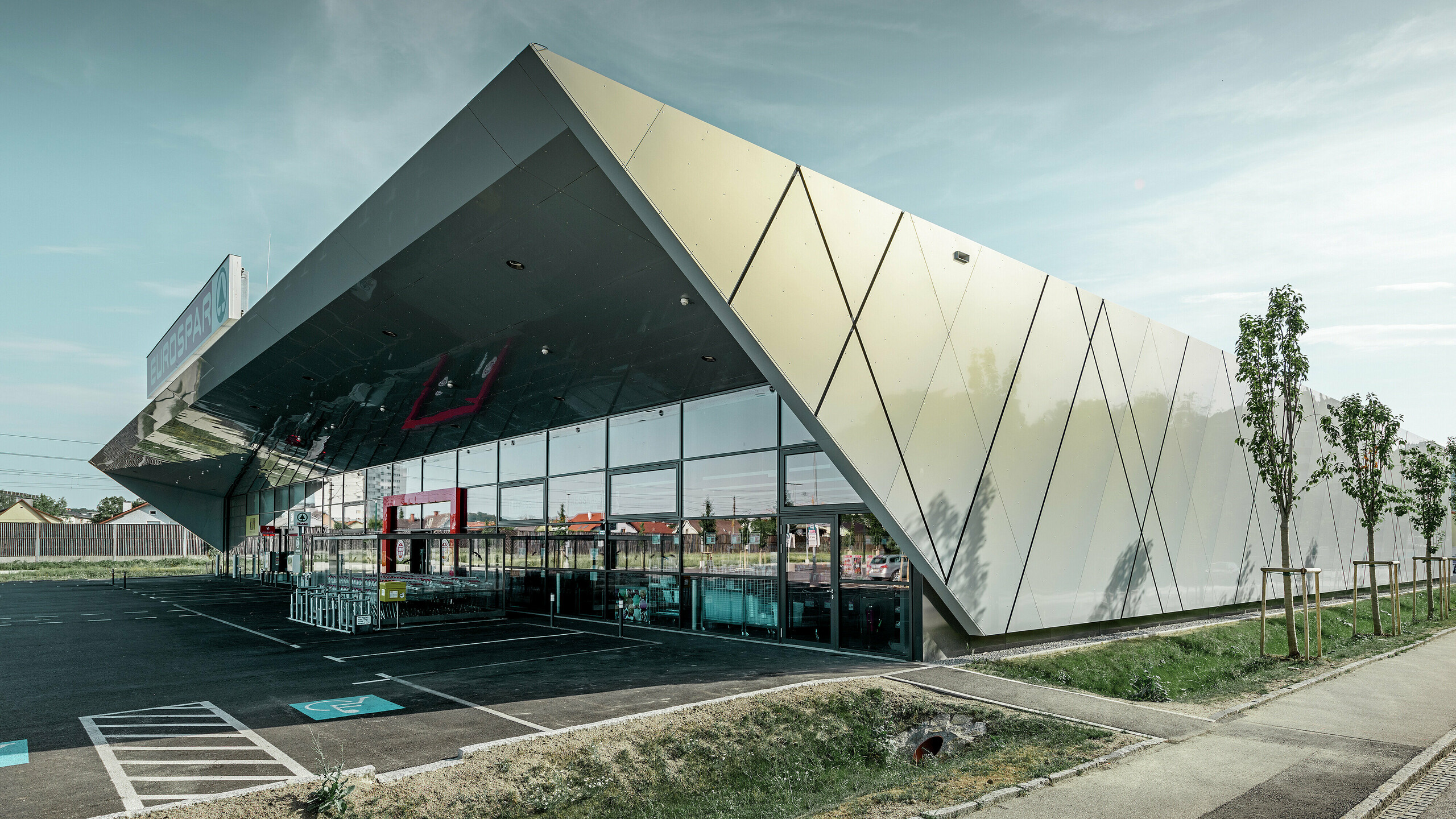 Indgangsparti til den nye Eurospar filial i Wels med den moderne facadeplade fra PREFA i sølv/guld. Alt efter synsvinklen glitrer aluminiumkompositpladerne i forskellige farver i solen.