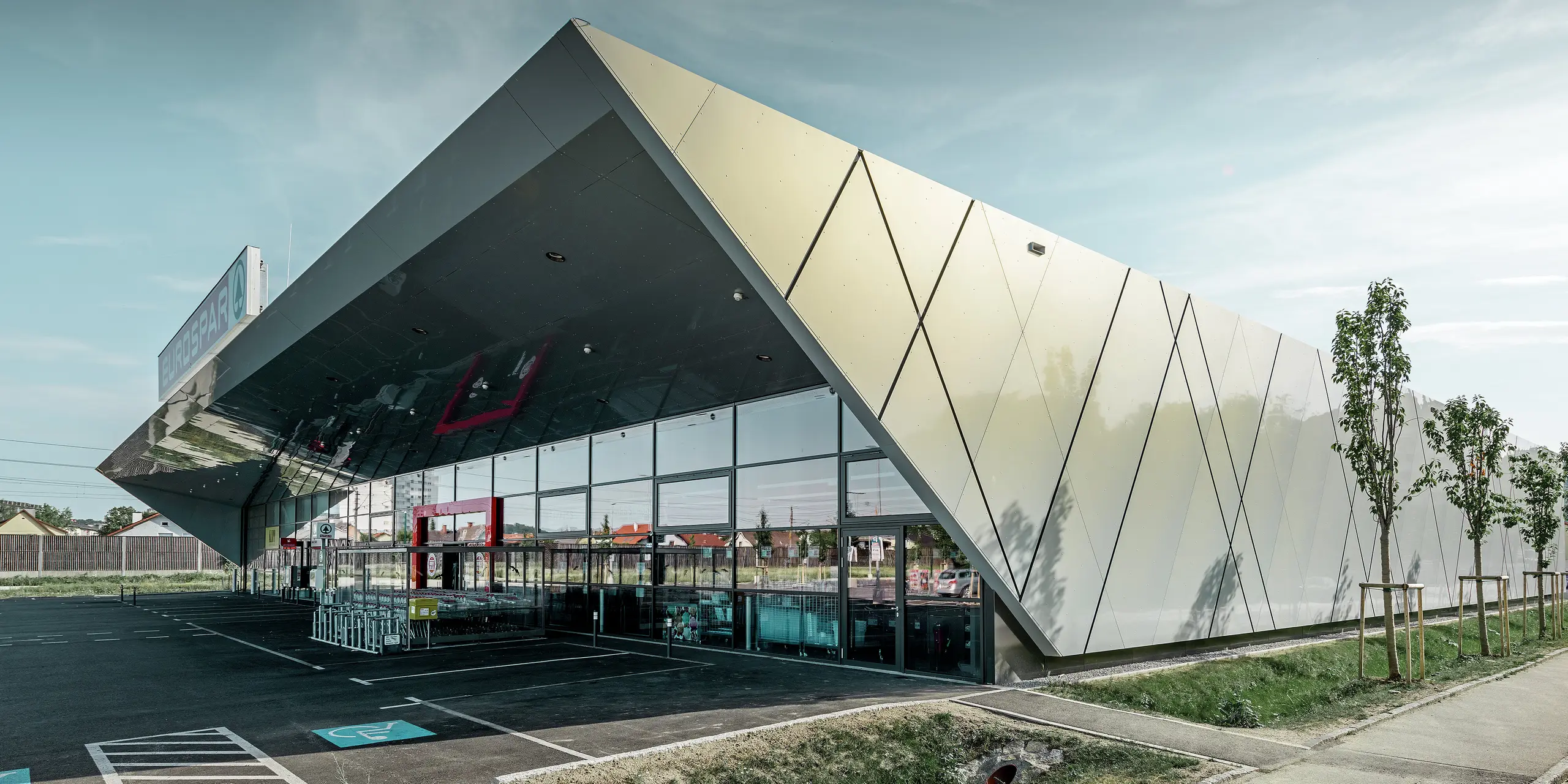 Indgangsparti til den nye Eurospar filial i Wels med den moderne facadeplade fra PREFA i sølv/guld. Alt efter synsvinklen glitrer aluminiumkompositpladerne i forskellige farver i solen.
