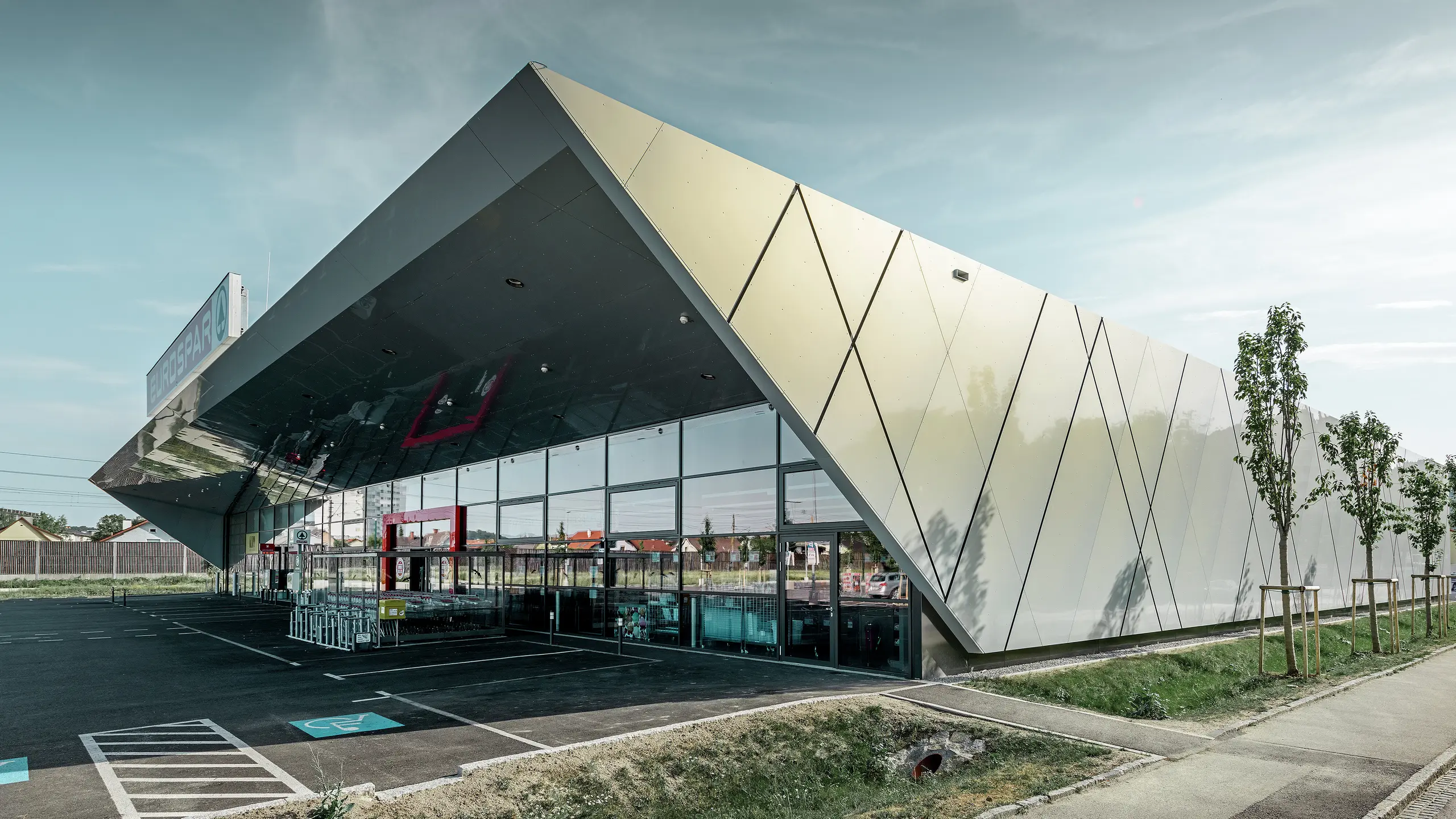 Indgangsparti til den nye Eurospar filial i Wels med den moderne facadeplade fra PREFA i sølv/guld. Alt efter synsvinklen glitrer aluminiumkompositpladerne i forskellige farver i solen.