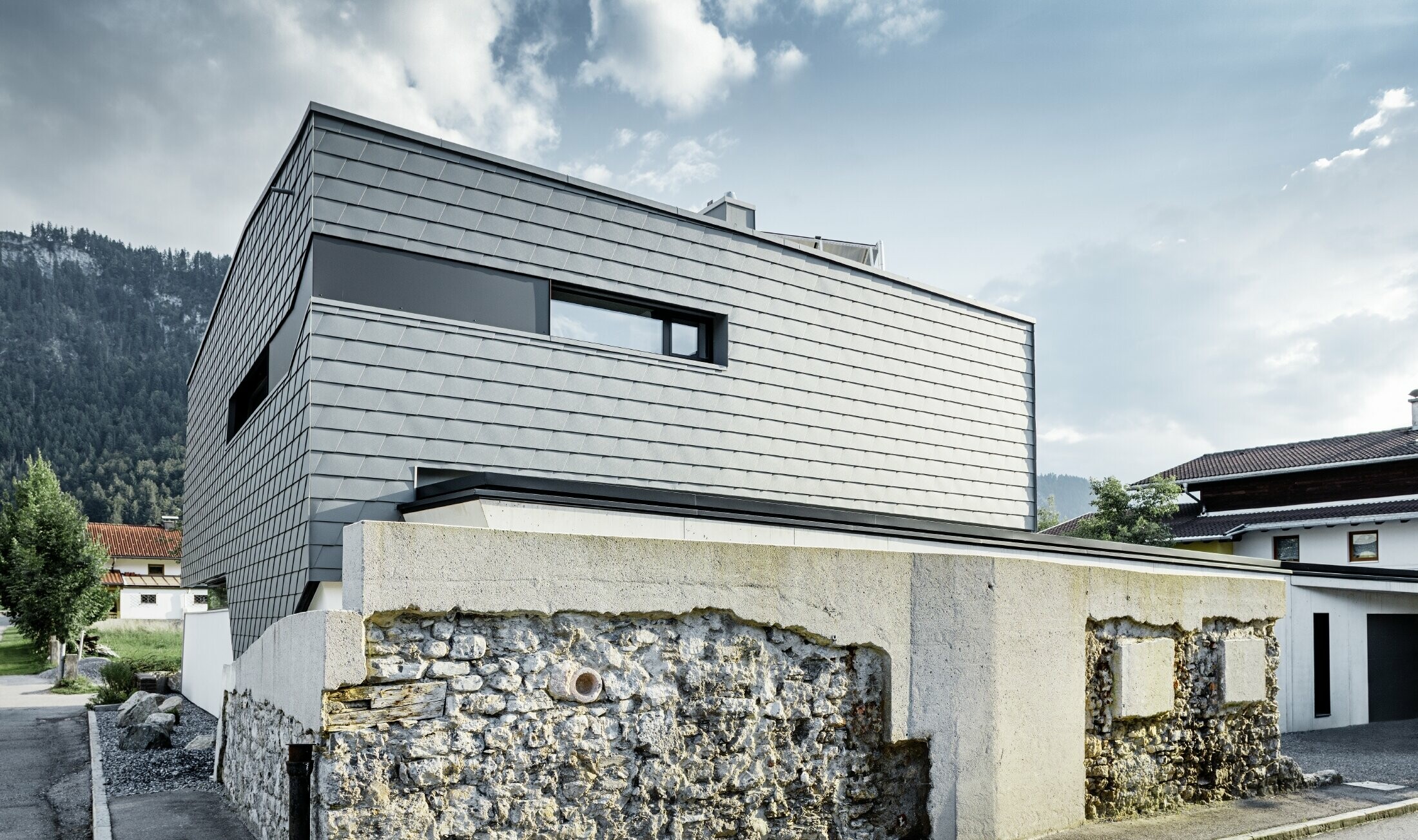 Moderne enfamiliehus med fladt tag, store vinduesflader og en vægspån-facade i lysegrå af aluminium fra PREFA