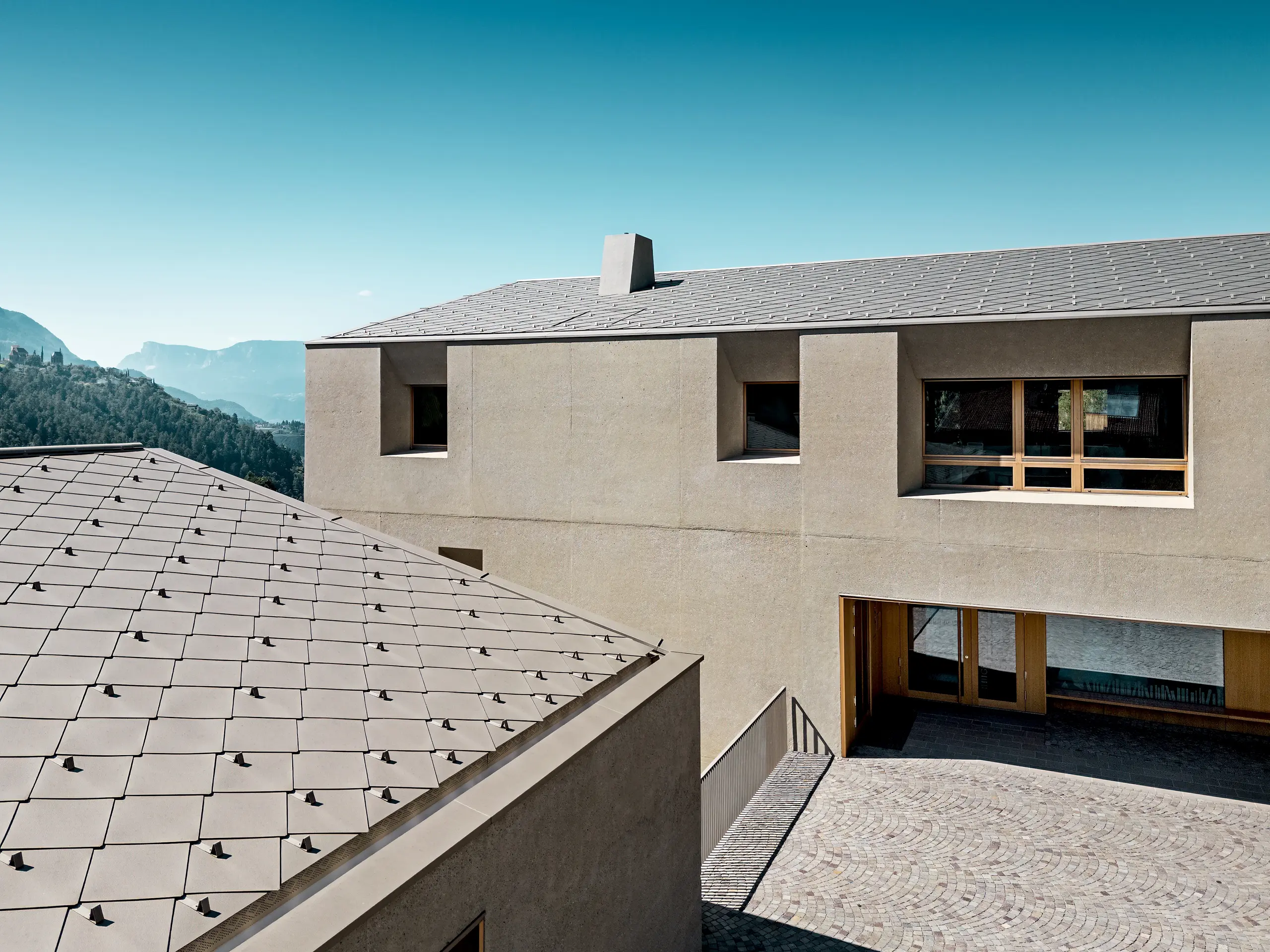 Detailansicht des Bildungszentrums Riffian mit PREFA Dachrauten 44 × 44 in P.10 Bronze. Die präzise Aluminiumdeckung auf den klar gestalteten Baukörpern unterstreicht die moderne Architektur, bietet langlebigen Witterungsschutz und verbindet sich harmonisch mit der natürlichen Südtiroler Bergkulisse.