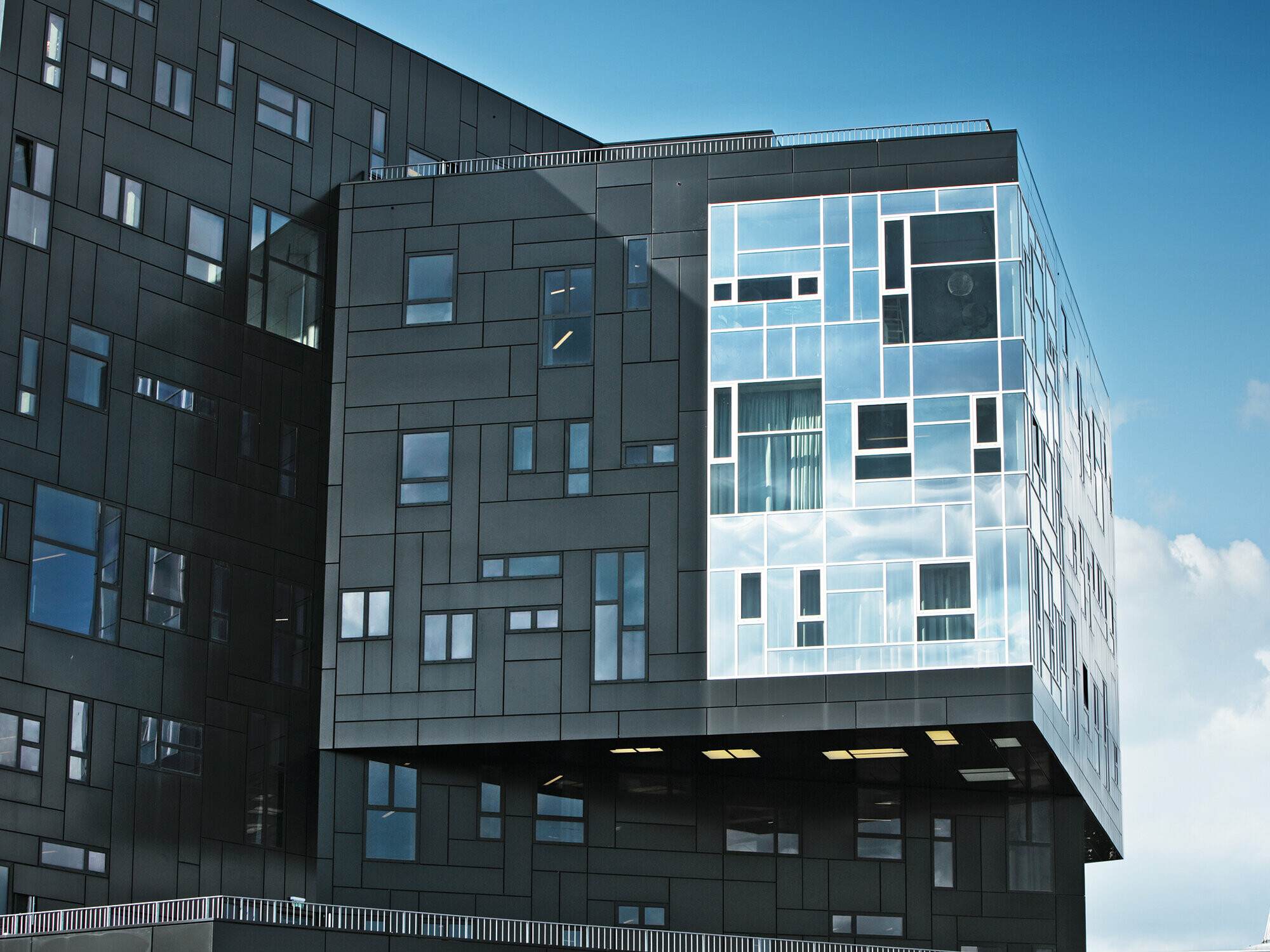 Optagelse af WU Executive Academy med fokus på PREFA aluminiumskompositpladenfacaden i dyb sort og den skinnende vinduessektion.