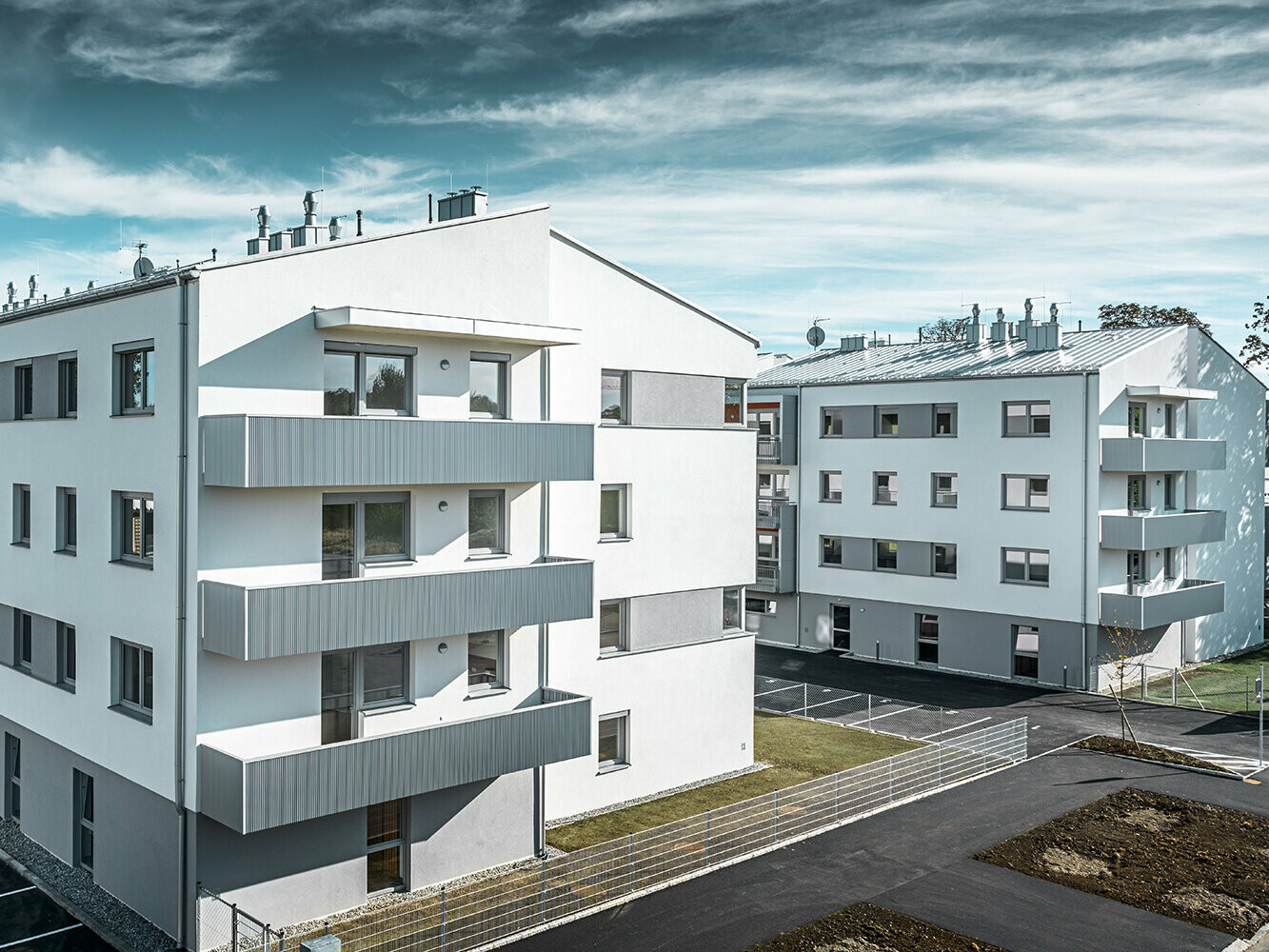 Moderne boligbyggeri med hvid facade og balkoner med takket PREFA-profil i sølvmetallic