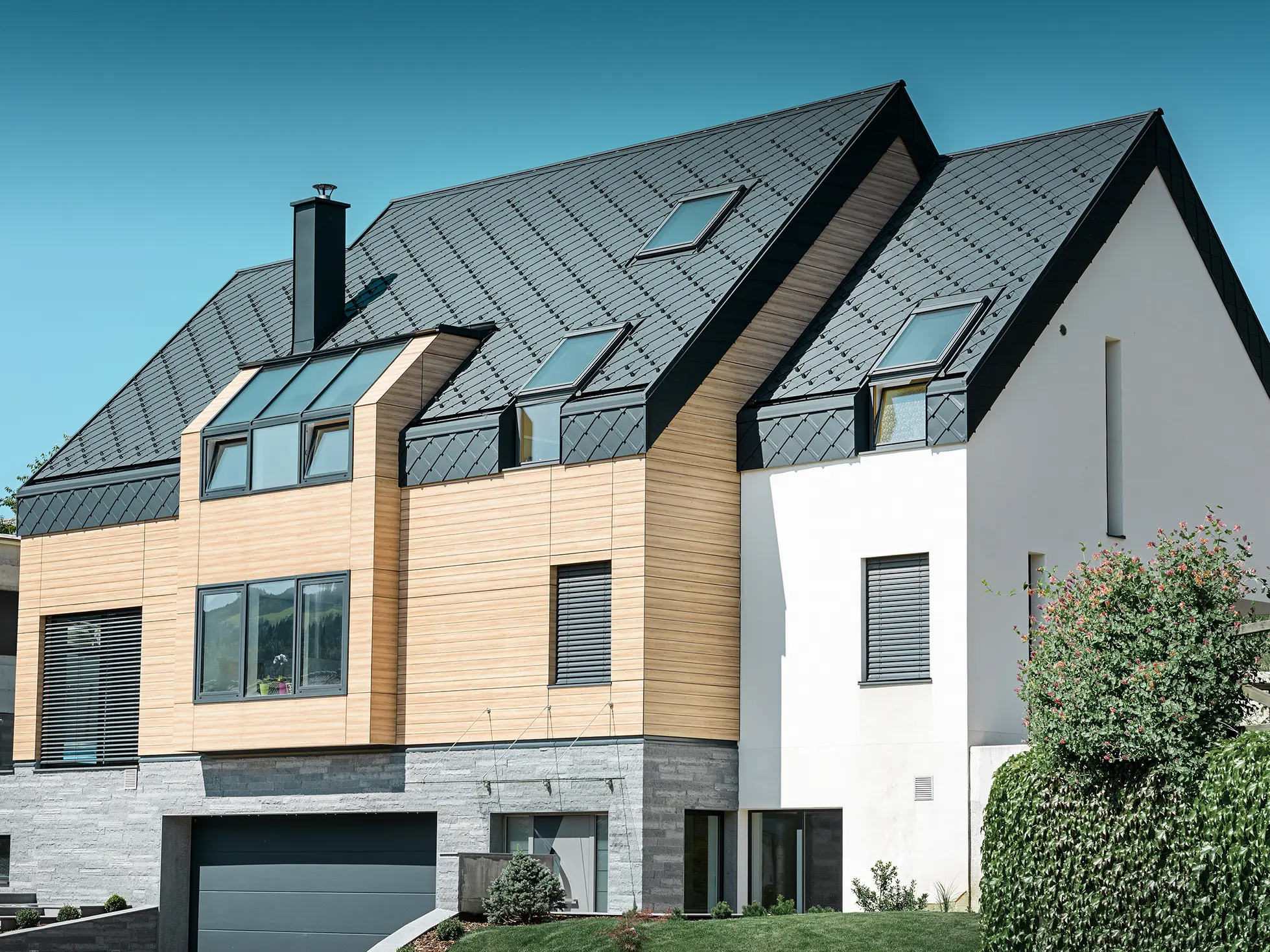 Moderne nybyggeri, hvor tagbeklædningen også dækker den øverste del af facaden. Til tagbeklædningen er der anvendt aluminiumstagromber i antracit