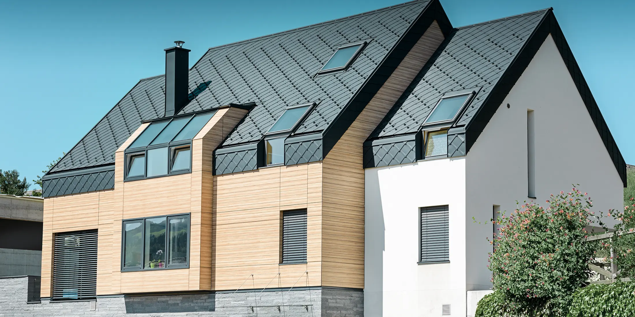 Moderne nybyggeri, hvor tagbeklædningen også dækker den øverste del af facaden. Til tagbeklædningen er der anvendt aluminiumstagromber i antracit