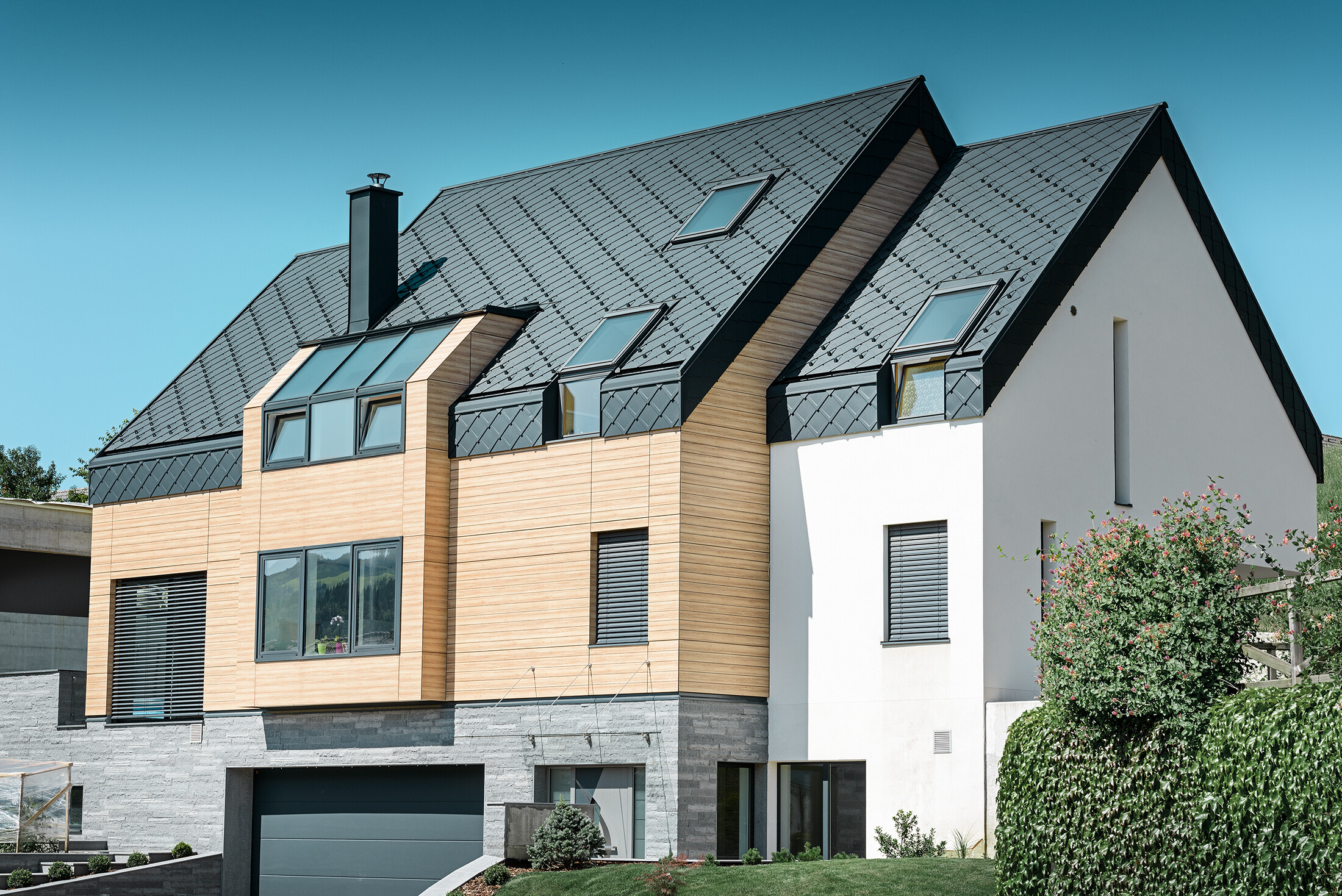 Moderne nybyggeri, hvor tagbeklædningen også dækker den øverste del af facaden. Til tagbeklædningen er der anvendt aluminiumstagromber i antracit