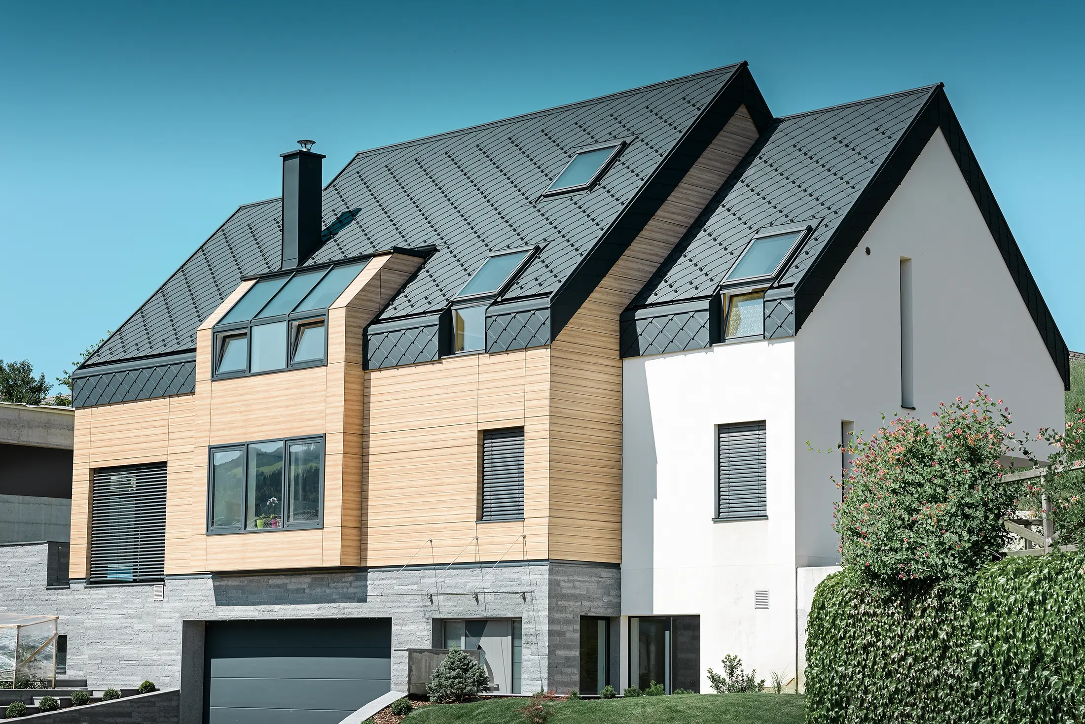 Moderne nybyggeri, hvor tagbeklædningen også dækker den øverste del af facaden. Til tagbeklædningen er der anvendt aluminiumstagromber i antracit