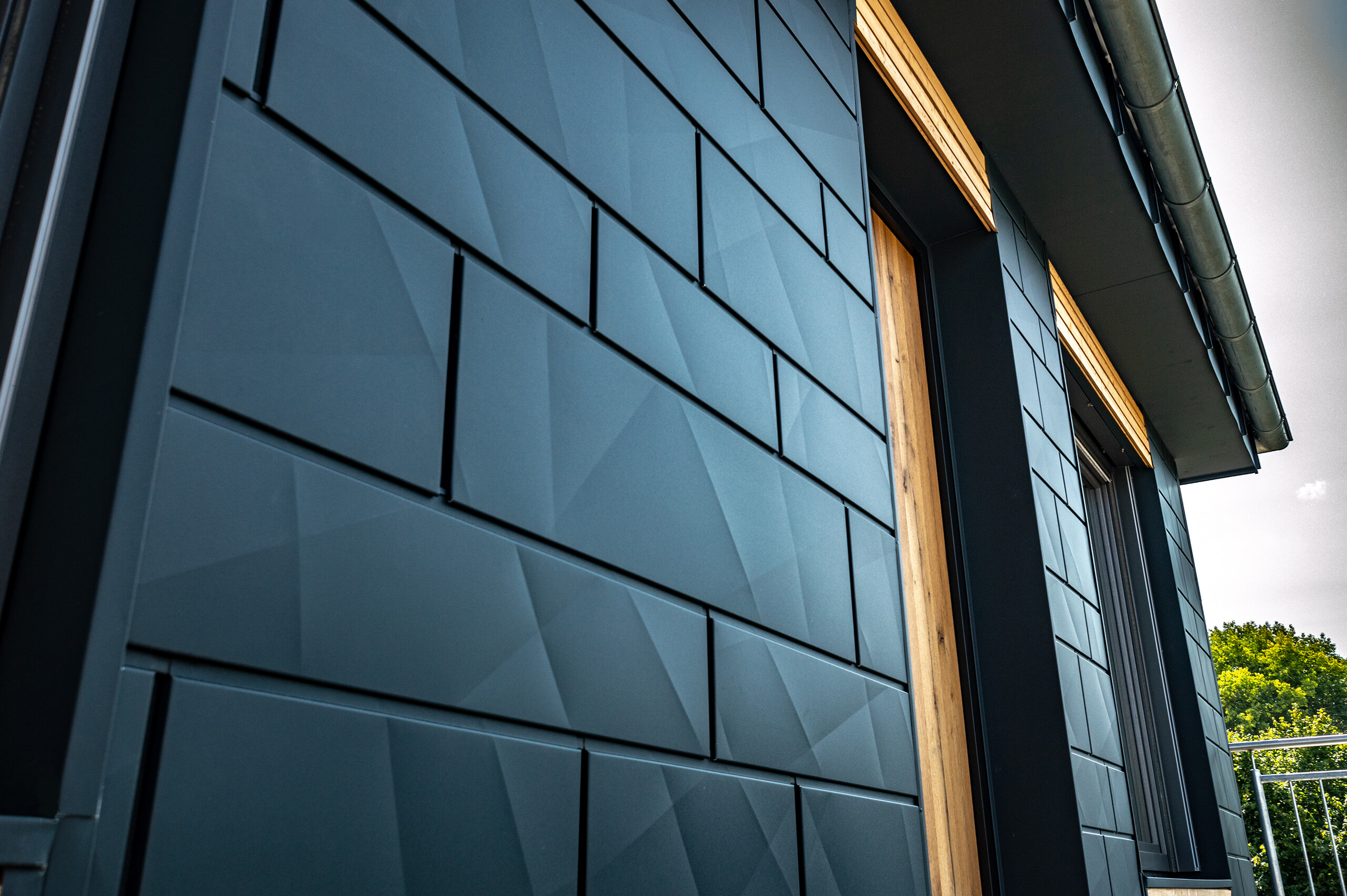 Facade med PREFA Siding.X i antracit med altandøre og store glasflader blandet med en træfacade.