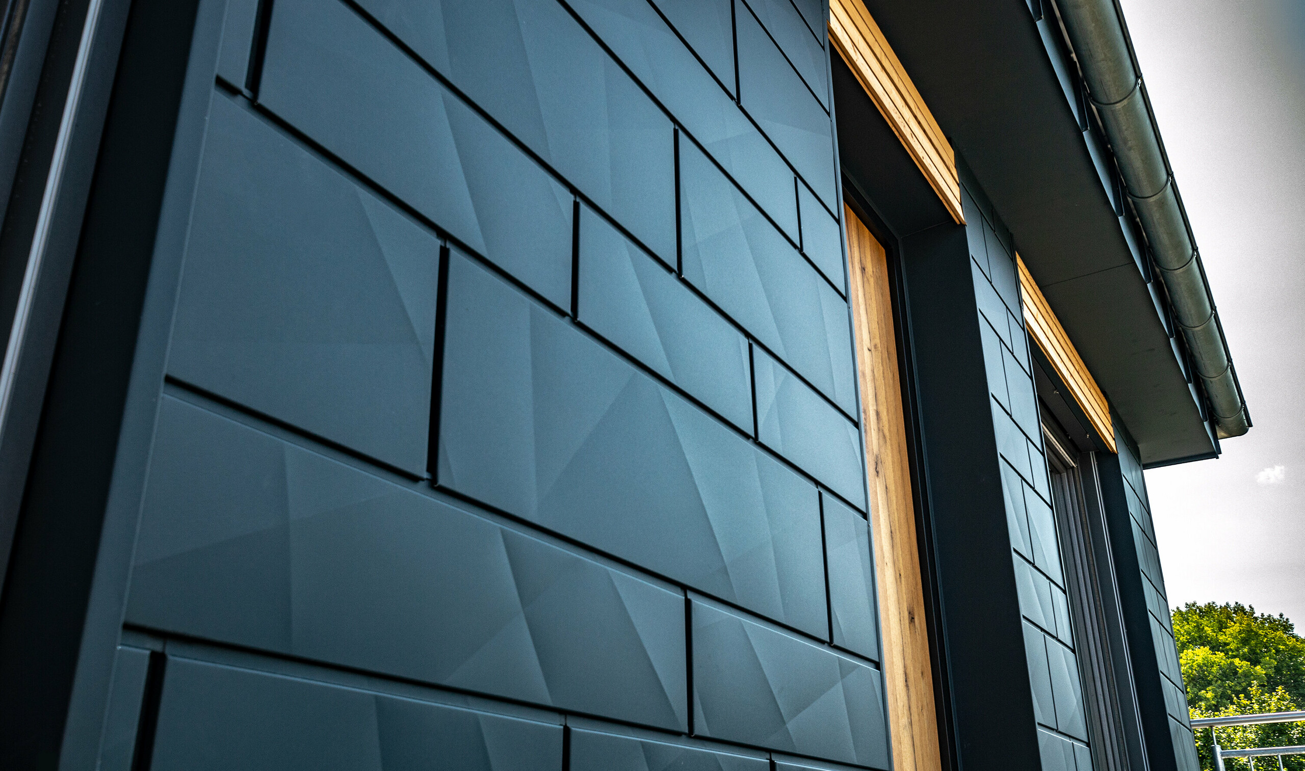 Facade med PREFA Siding.X i antracit med altandøre og store glaspartier blandet med en træfacade.