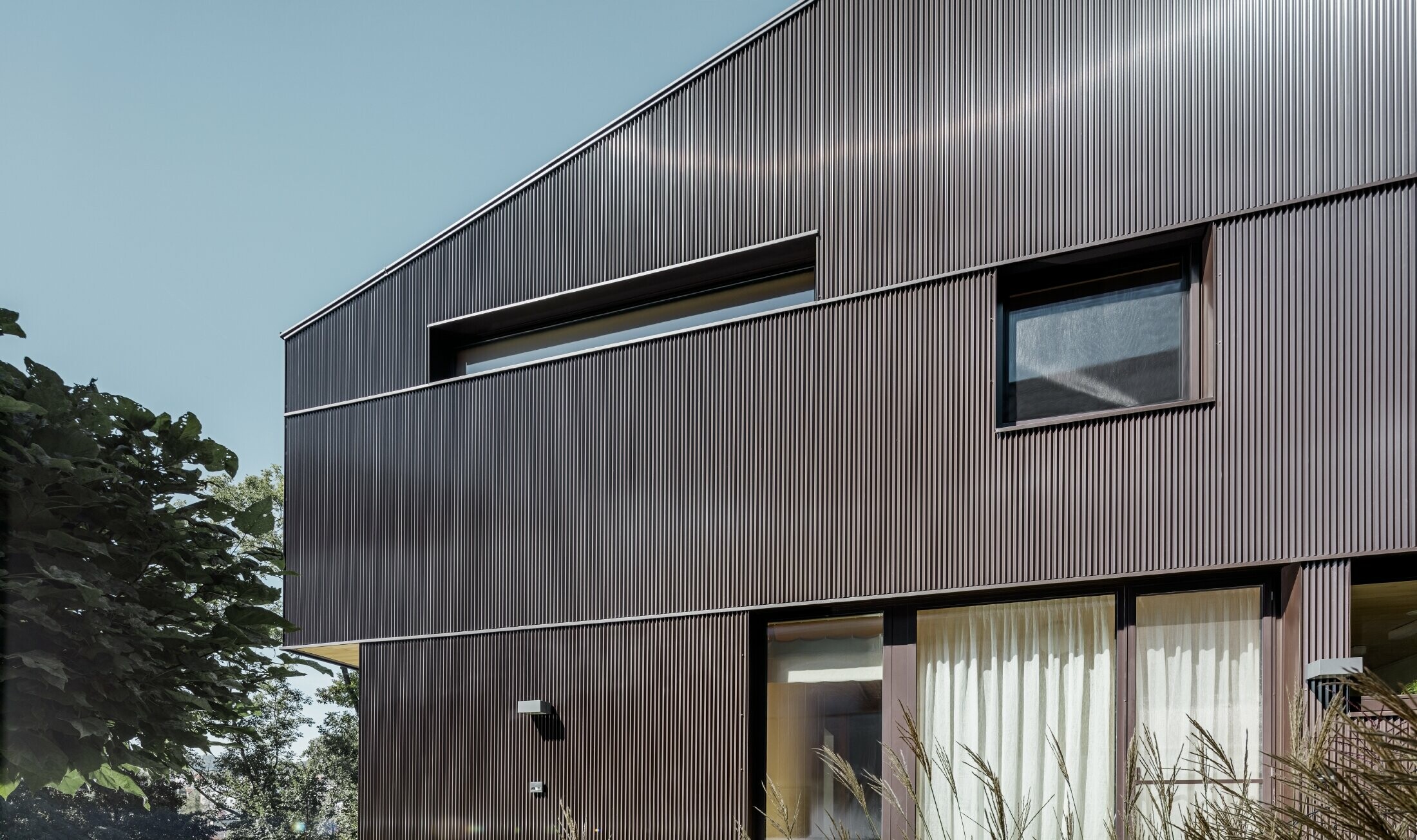 Moderne enfamilieshus med en facadebeklædning fra PREFA - takket profil i brun.