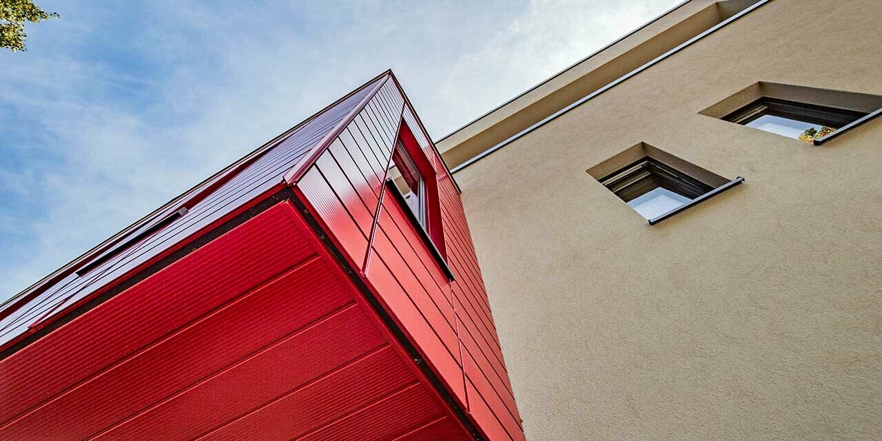 Karnap med linjeret PREFA Siding i rubinrød på et moderne enfamilieshus i Wernigerode, her er den udhængende tilbygning fotograferet nedefra.