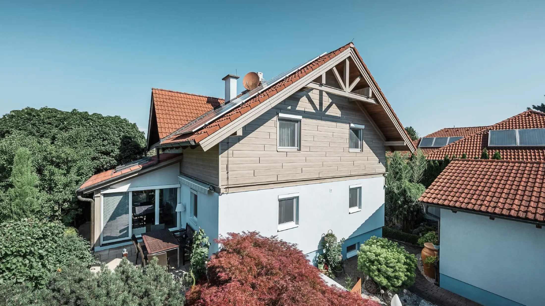 Facaden på et enfamiliehus, hvor øverste etage er beklædt med Sidings i trælook i farven beige/grå eg