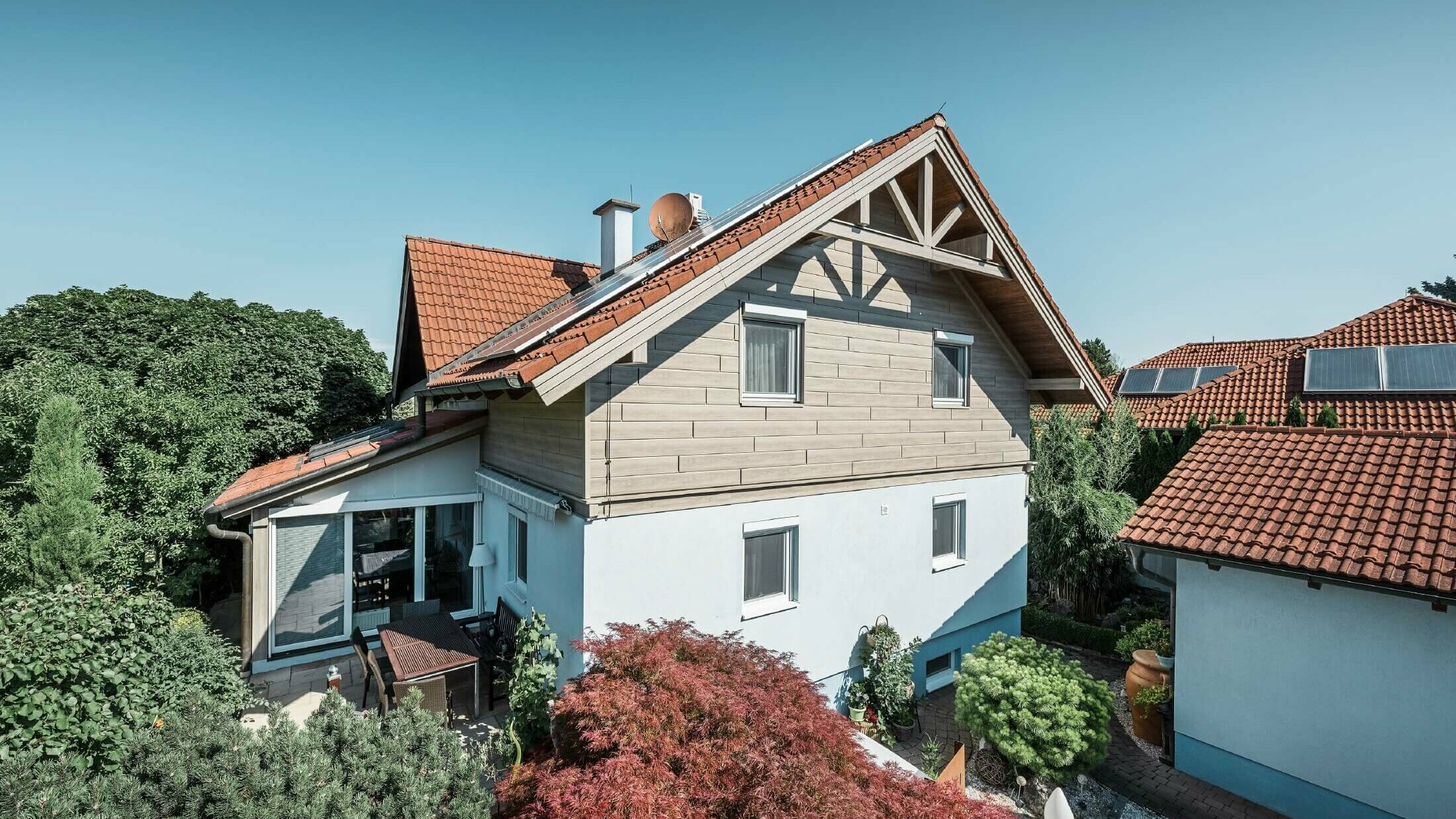 Facaden på et enfamiliehus, hvor øverste etage er beklædt med Sidings i trælook i farven beige/grå eg