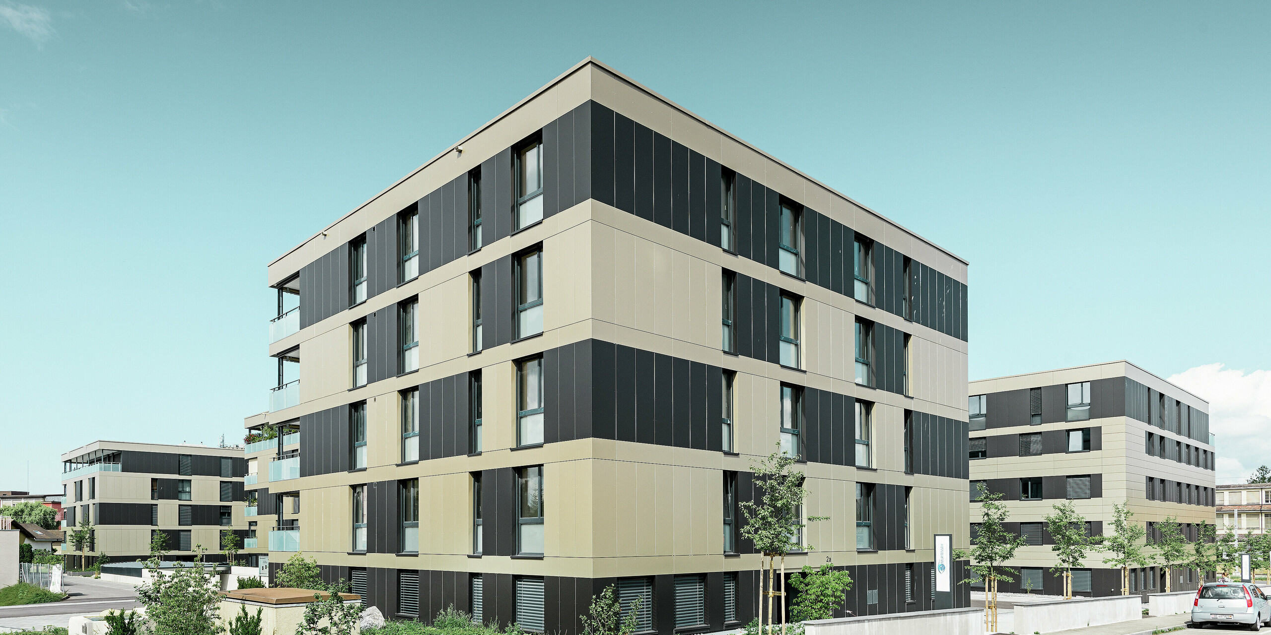 Terningformet boliganlæg med en aluminiumfacade i bronze med sortgrå elementer