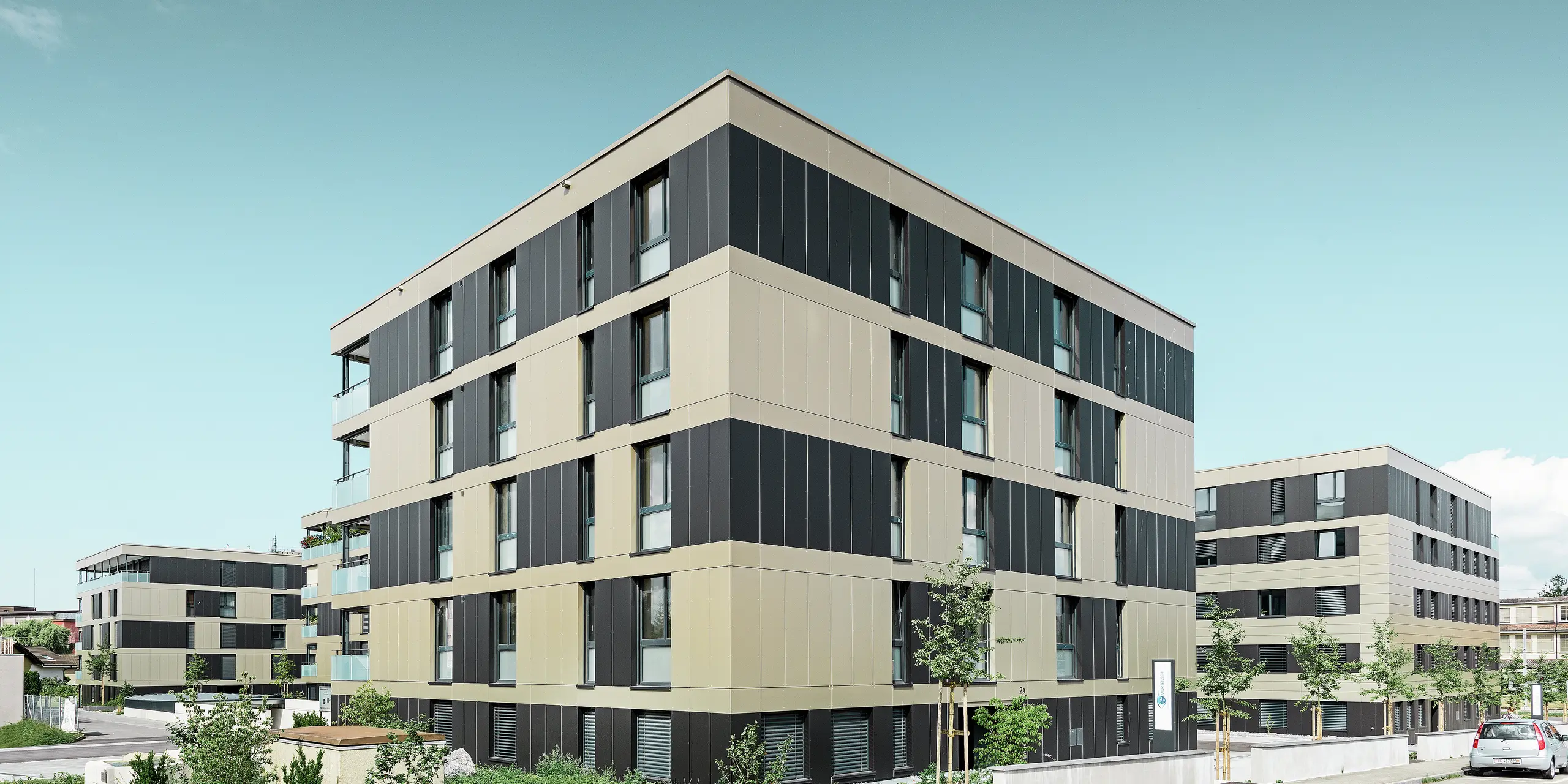 Terningformet boliganlæg med en aluminiumfacade i bronze med sortgrå elementer