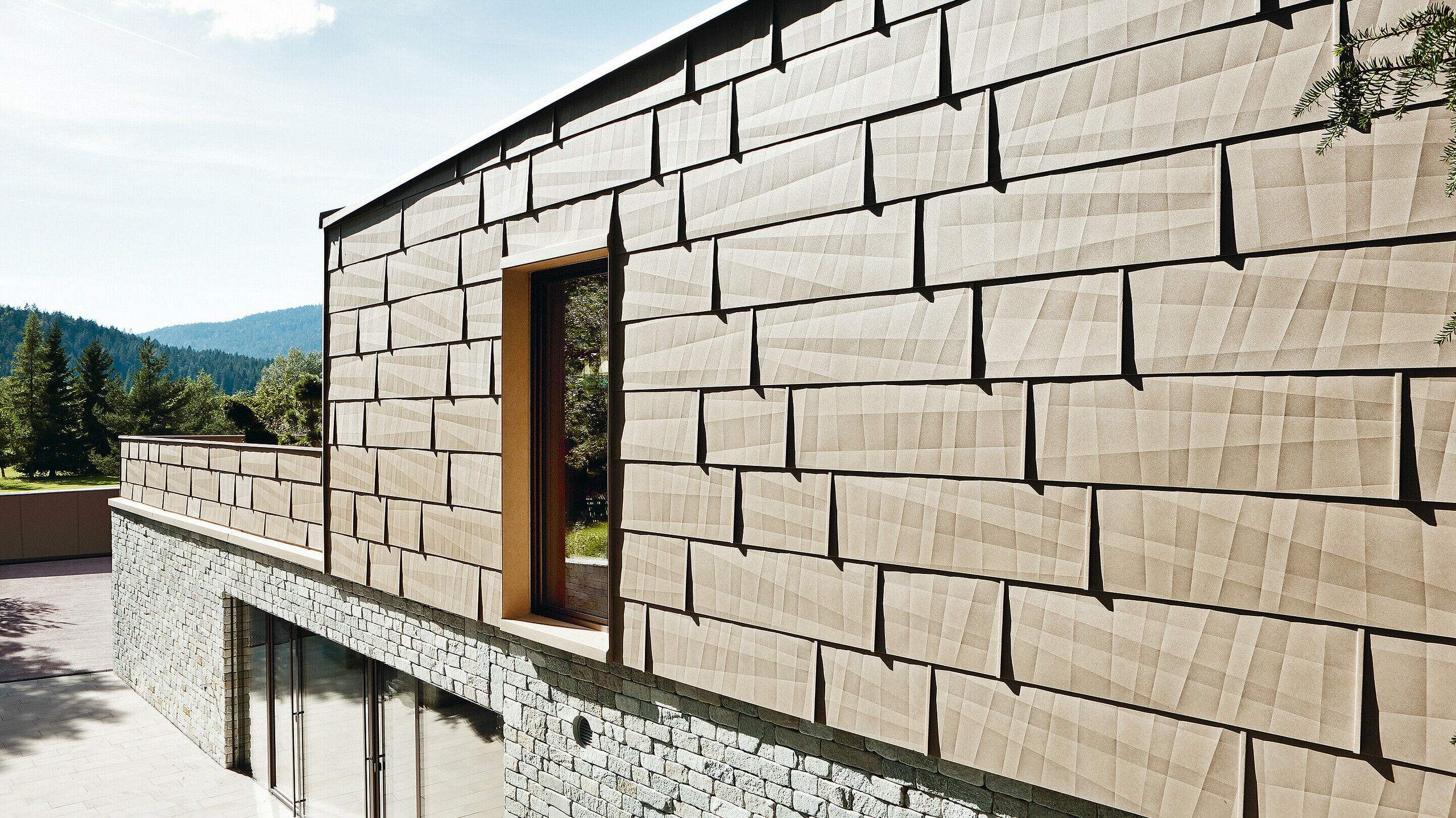 Facade i en kombination af PREFA facadepanel FX.12 i P.10 sandbrun og stenfacade på underetagen.