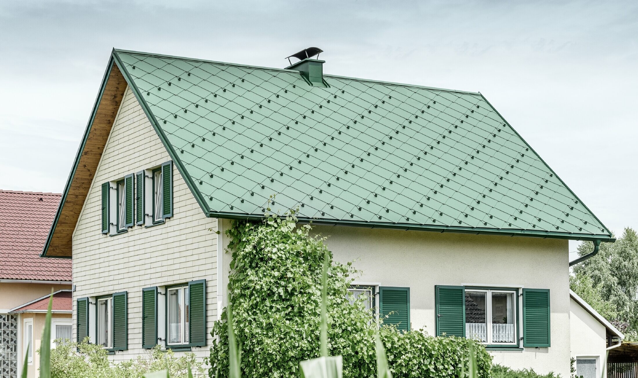 Klassisk enfamilieshus med sadeltag med en taginddækning af aluminium fra mosgrøn med grønne vinduesskodder