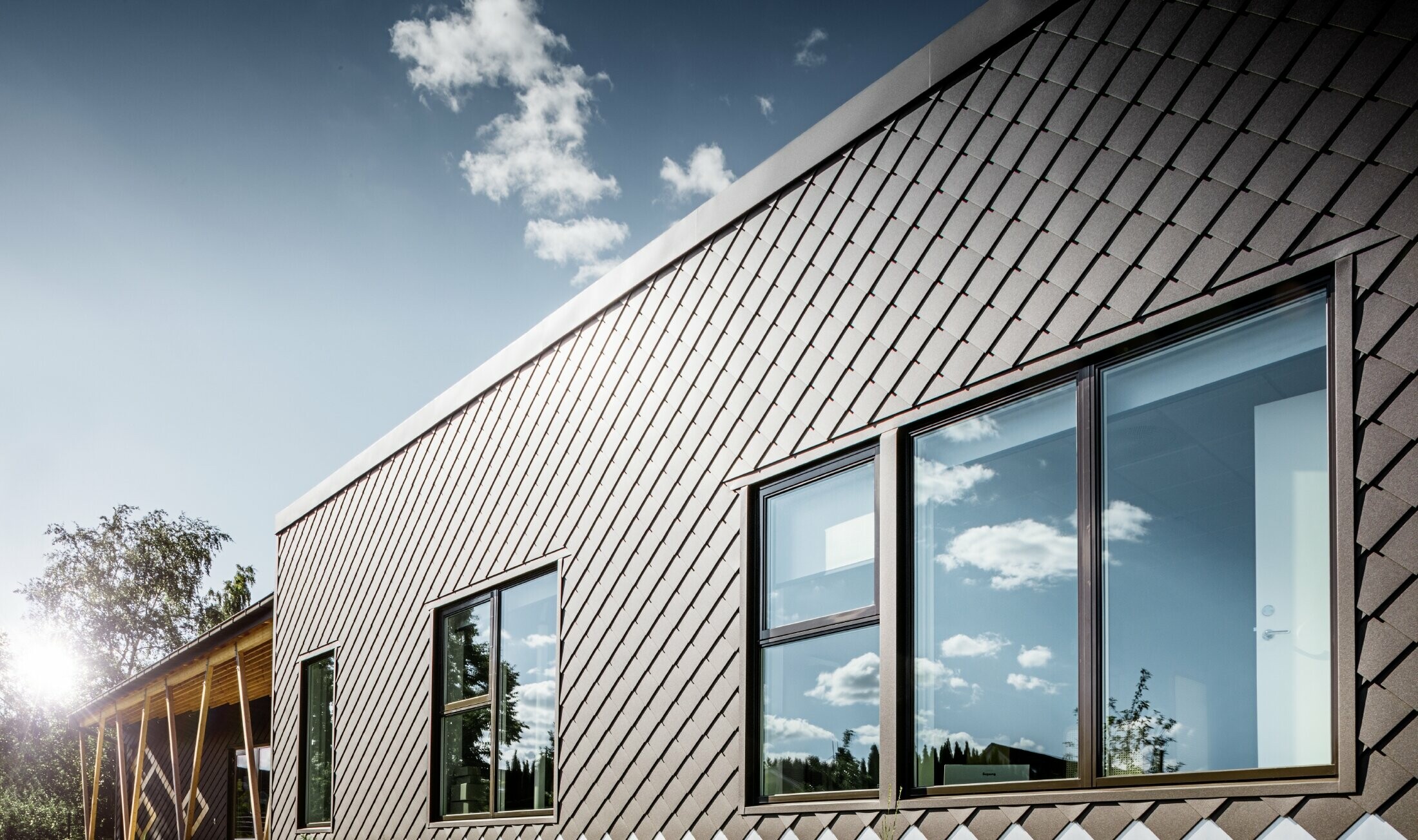 Denne indgang til forskolen i Stokholm viser den nye facade med stor vinduesflade og fladt tag. Den udvendige facade blev beklædt med facaderombe 20 x 20 i brun.