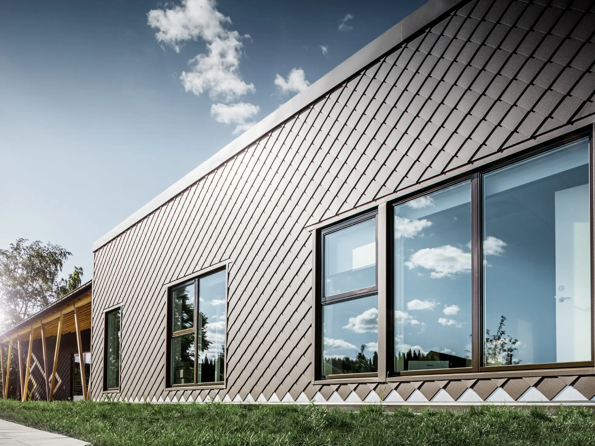 Denne indgang til forskolen i Stokholm viser den nye facade med stor vinduesflade og fladt tag. Den udvendige facade blev beklædt med facaderombe 20 x 20 i brun.
