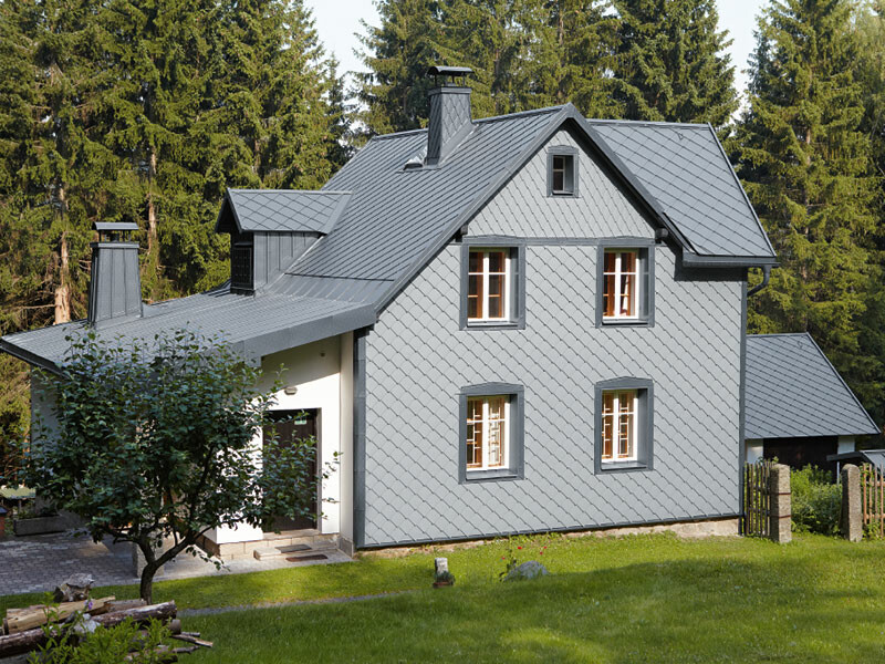 Enfamilieshus i skovområde med vejrbestandig PREFA-aluminiumsfacade i lys grå.