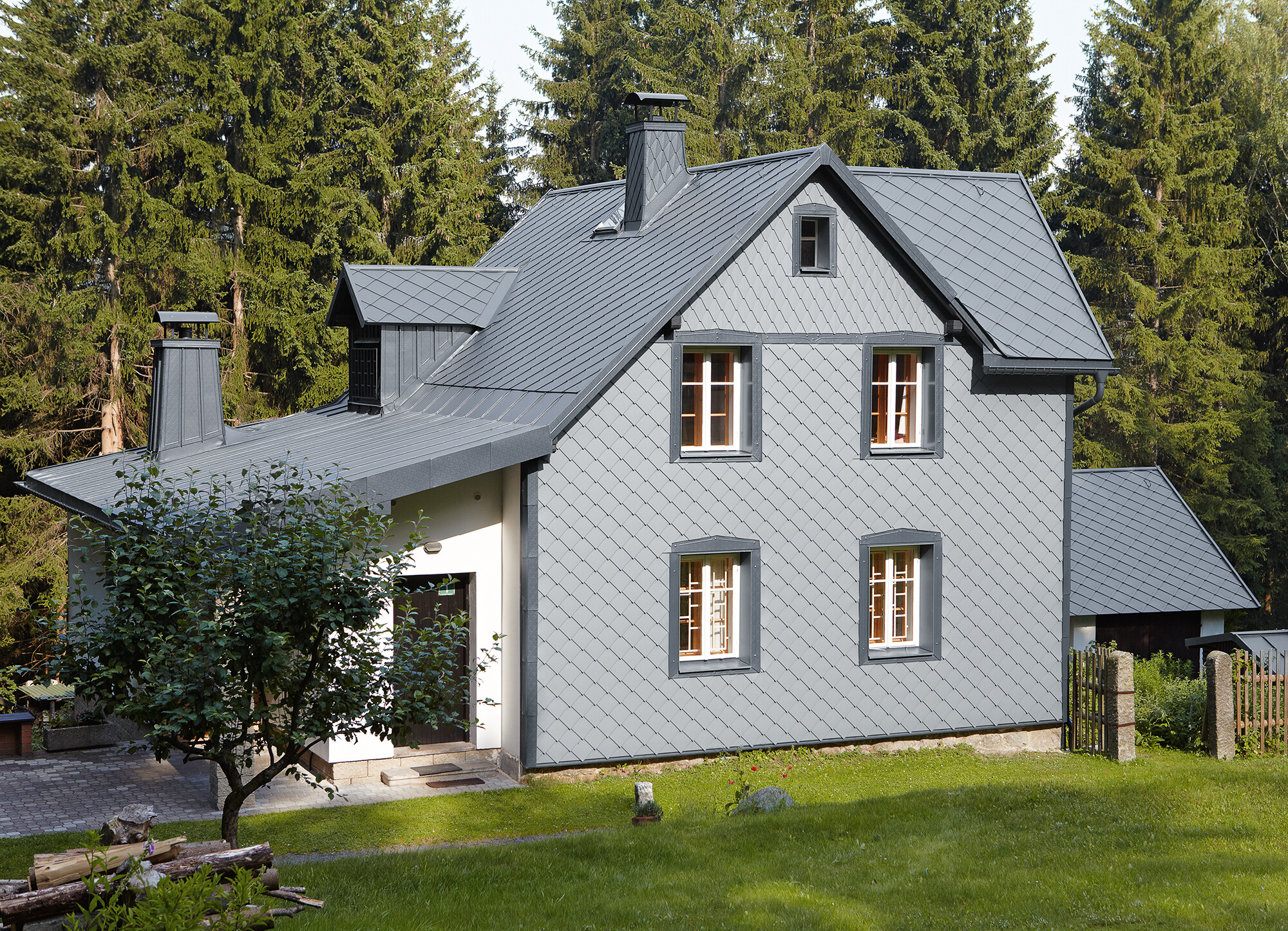 Facade med PREFA-vægrombe 29 × 29 i lys grå på vejrsiden Enfamilieshus i skovområde med vejrbestandig PREFA-aluminiumsfacade i lys grå.