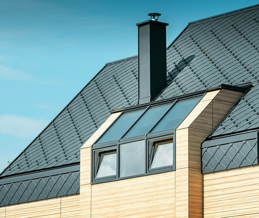 Enfamilieshus med sadeltag uden udhæng med en facade i træ-look og aluminiumstag i antracit