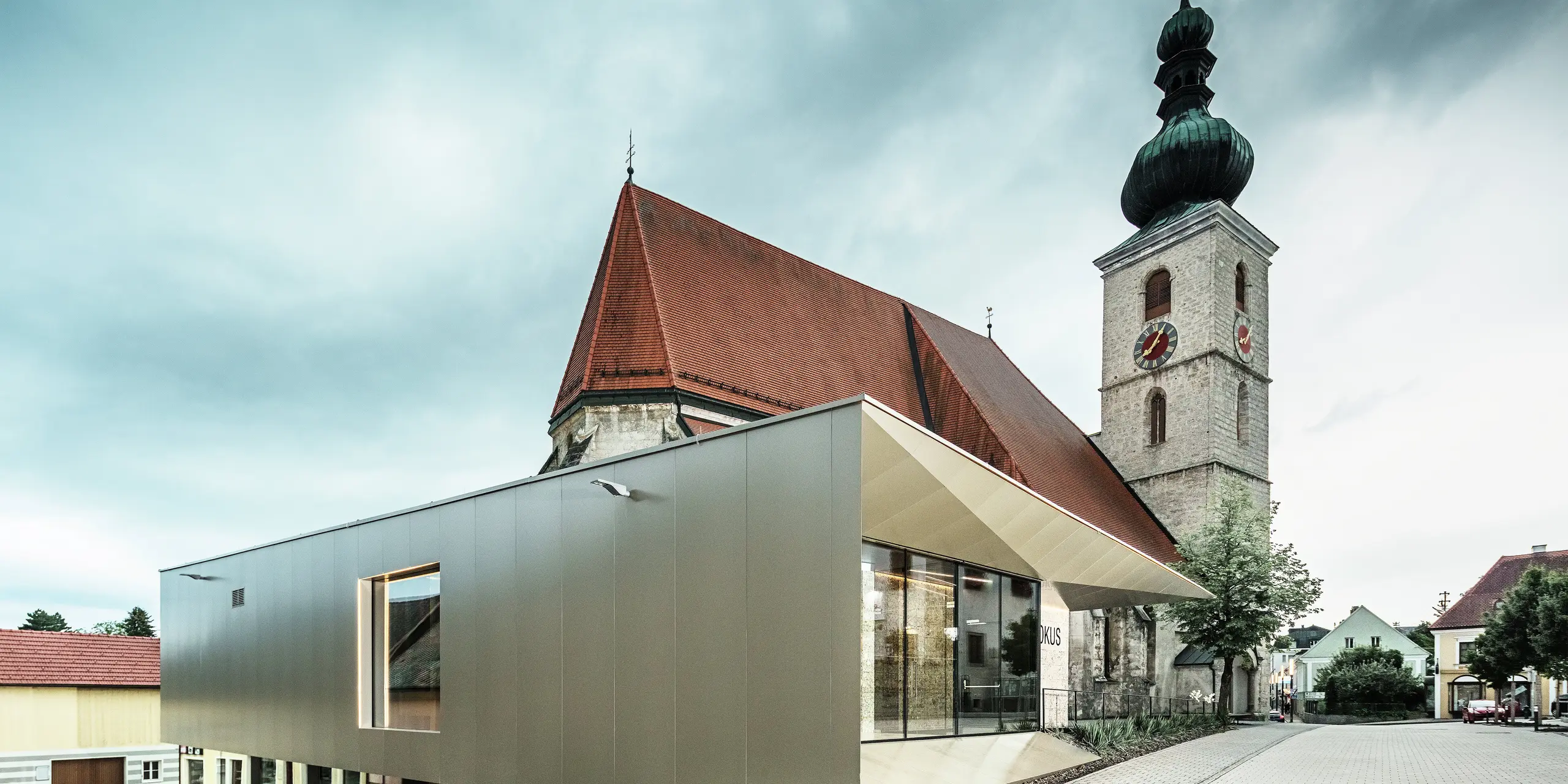 Set fra siden ses det filigrane tagudhæng, der er realiseret med højkvalitets PREFA aluminiumskompositplader. Den præcise udførelse giver et moderne udseende med klare linjer og understreger den arkitektoniske forbindelse mellem gammelt og nyt.