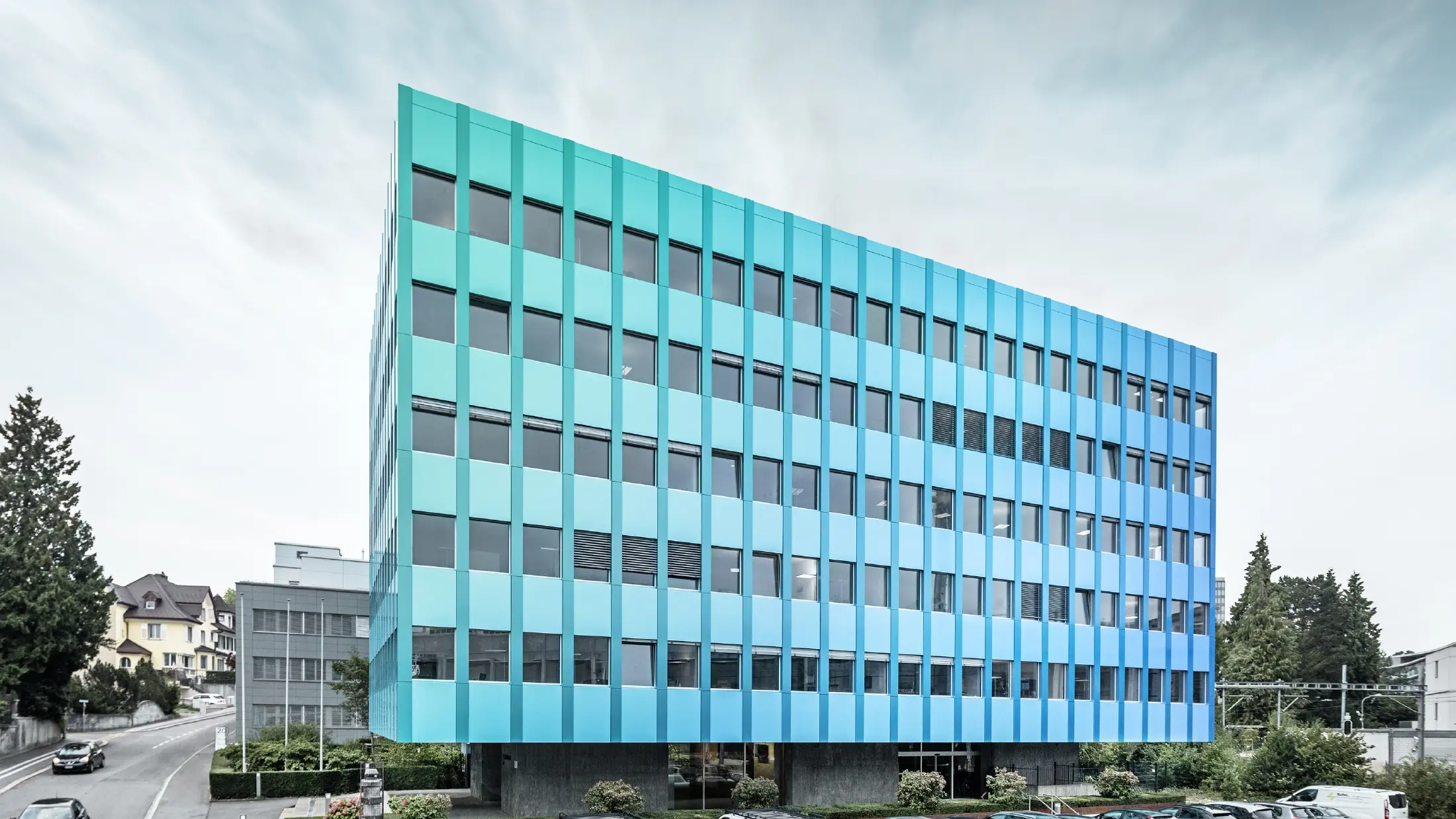 Sidebillede af Wielandhuset i Aarau; Facaden er beklædt med PREFABOND-aluminiumskompositplade fra PREFA, som takket være den specielle belægningsproces skimrer i blågrønne nuancer.
