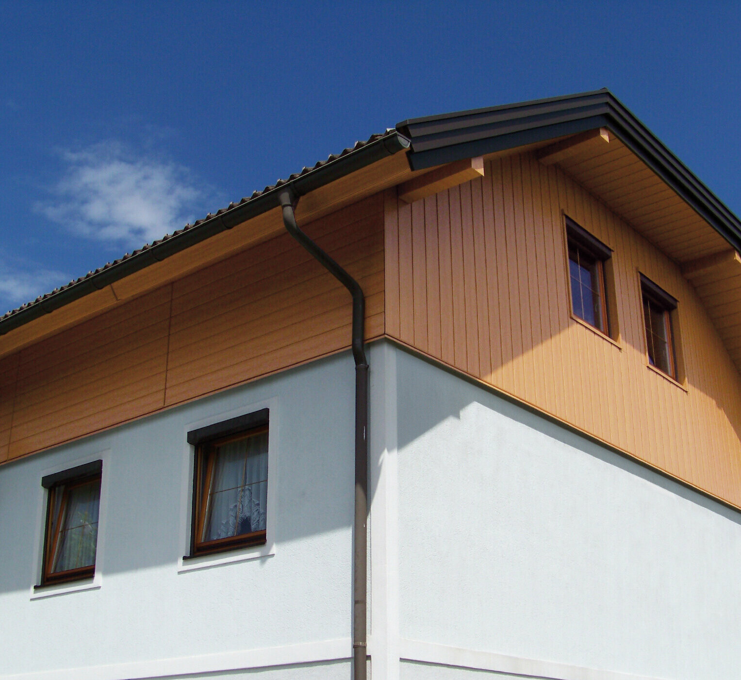 Stort enfamiliehus med halvvalmtag og gavlbeklædning med PREFA Sidings i trælook (naturlig eg)