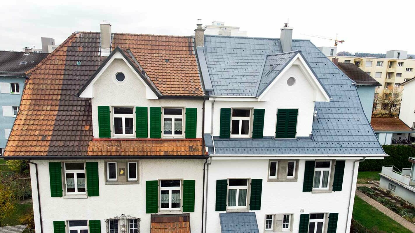 Dobbelthus i Schweiz; Husets venstre del er endnu ikke blevet renoveret og stadig dækket med plettede tegl. Husets højre del er belagt med PREFA tagplader i stengrå.